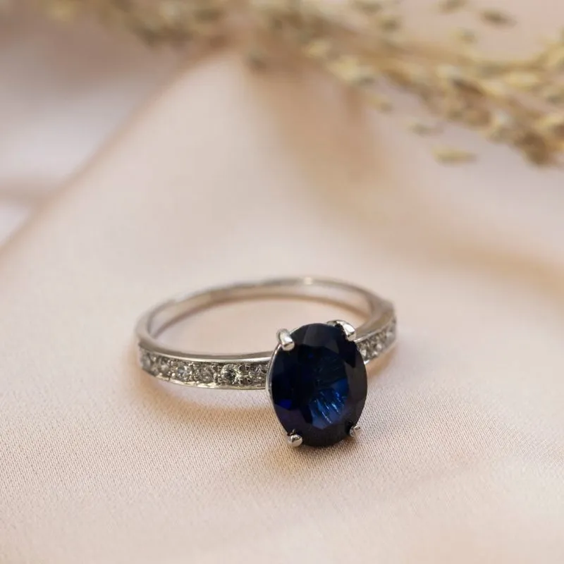 White gold ring with white zircons and a prominent oval blue stone