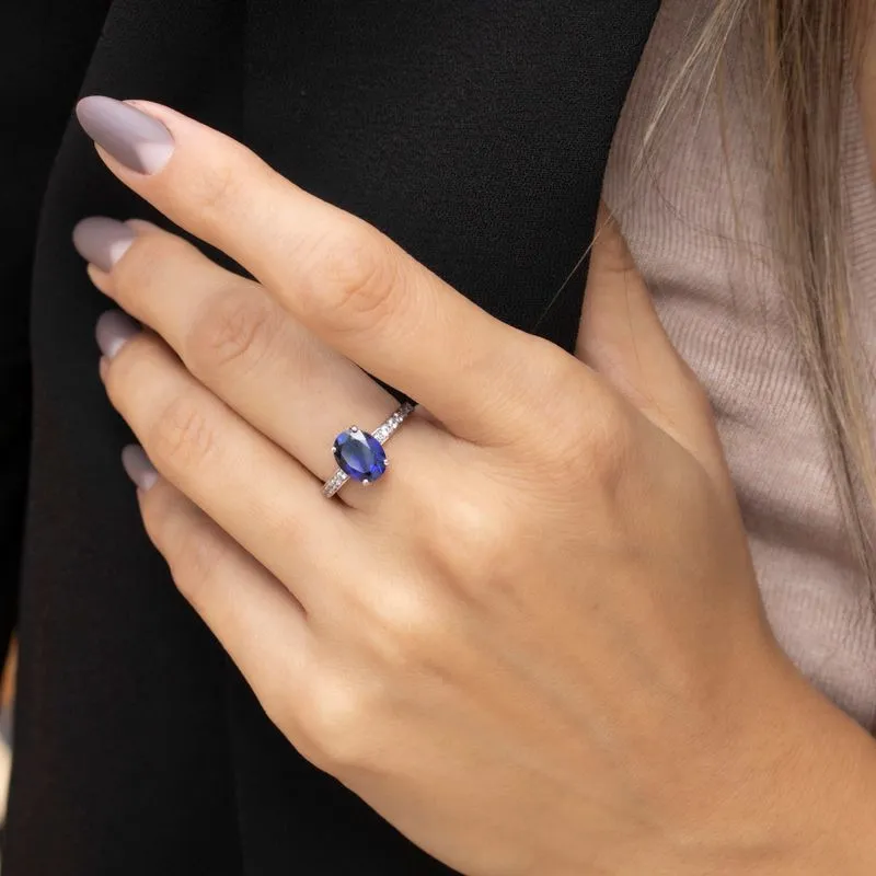 White gold ring with white zircons and a prominent oval blue stone